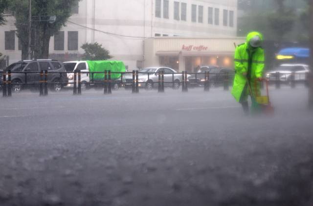 지난 16일 폭우가 쏟아진 서울 서대문구에서 환경미화원이 인도를 청소하고 있다. 연합뉴스