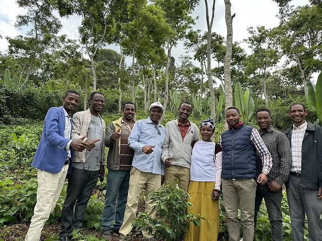 한국 산림청 지원 커피 혼농임업 사업지 현장의 농장 주인과 협력파트너들 (코체리<에티오피아>=연합뉴스) 김성진 기자 = 지난달 27일(현지시간) 에티오피아 남부 오로미아주 코체리 지구에서 한국 산림청이 후원한 커피혼농임업 사업 관계자들과 농장 부부(왼쪽에서 5번째 남녀) 등이 신품종 커피 묘목 앞에서 포즈를 취하고 있다. sungjin@yna.co.kr 2025.6.21