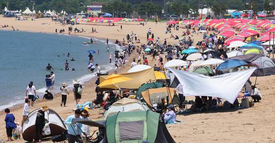 장마가 잠시 소강 상태를 보인 22일 인천 중구 왕산해수욕장을 찾은 시민들이 더위를 식히고 있다. 인천지역 주요 해수욕장은 지난 21일 중구 을왕리·왕산·하나개 해수욕장 개장을 시작으로 11개소가 순차적으로 개장한다. 연합뉴스