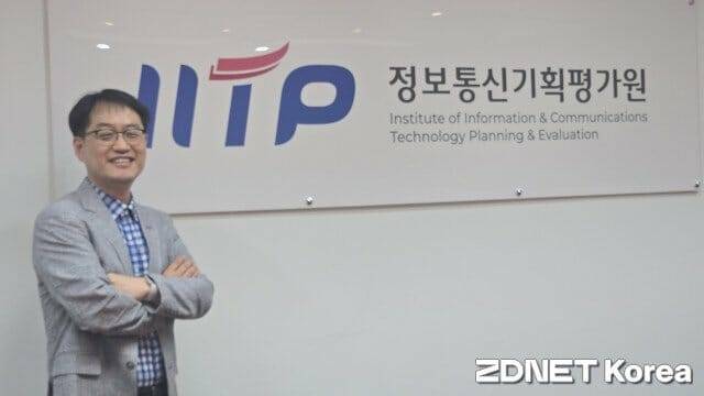 김창오 정보보안PM이 소속 공공기관인 IITP의 CI를 배경으로 포즈를 취했다.