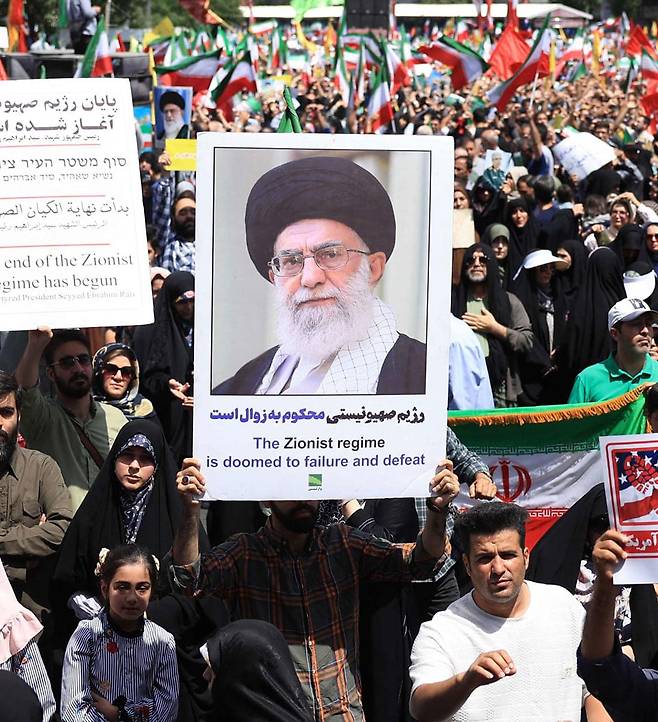 이란에선 하메네이 지지 시위 - 지난 20일(현지 시각) 이란 테헤란에서 최고 지도자인 아야톨라 알리 하메네이 초상화를 든 시민들이 이스라엘의 이란 공습에 항의하는 시위를 하고 있다. /AFP 연합뉴스