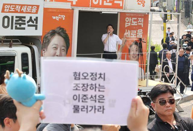 지난달 30일 이준석(가운데) 당시 개혁신당 대선 후보가 서울 동작구 중앙대학교에서 유세 중인 가운데, 일부 학생들이 이 후보의 여성 신체 관련 발언을 규탄하는 팻말을 들고 있다. 연합뉴스