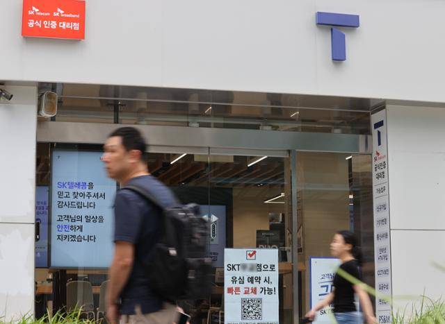 시민들이 SK텔레콤이 50일 만에 신규 가입자 대상 영업을 재개한 24일 서울 시내 한 SK텔레콤 T월드 대리점 앞을 지나고 있다. 연합뉴스