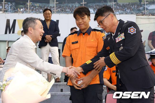 [OSEN=잠실, 최규한 기자] 24일 서울 잠실야구장에서 ‘2025 신한 SOL Bank KBO리그’ 두산 베어스와 SSG 랜더스의 경기가 열렸다.홈팀 두산은 최원준, 방문팀 SSG은 미치 화이트를 선발로 내세웠다.소방가족의 날 행사를 맞아 두산 박정원 구단주가 시구자로 나선 경북 119 산불대응단 손용원 소방교와 부친 손진복 소방경(대구지하철 참사 당시 소방 활동에 나선 바)에 꽃다발 전달하고 있다. 2025.06.24 / dreamer@osen.co.kr
