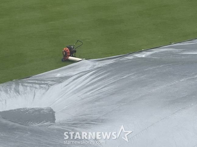 창원NC파크에 설치된 방수포의 물을 털어내고 있다. /사진=양정웅 기자
