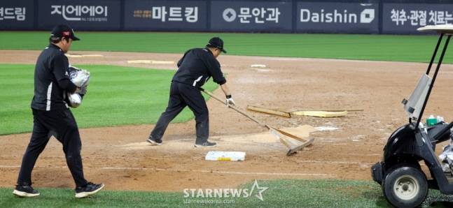 KT 그라운드 관리요원이 24일 수원KT위즈파크에서 열린 2025KBO리그 LG트윈스와 KT위즈의 경기에서 폭우가 쏟아져 6회초 수비를 마치고 경기가 중단된 가운데 비가 잦아들자 경기재개를 위해 그라운드를 정비하고 있다. /사진=강영조 선임기자