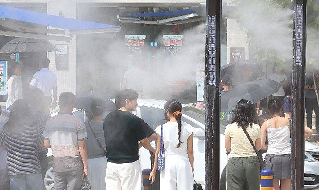 지난해 9월 폭염경보가 발효된 가운데, 부산역 앞 횡단보도를 지나는 시민들 사이로 쿨링포그가 가동되고 있다. 연합뉴스