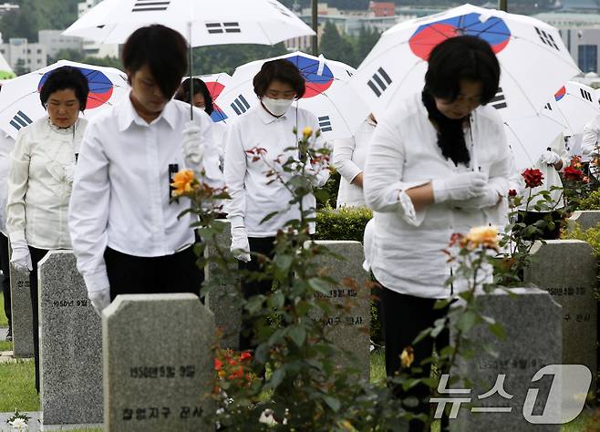 25일 오전 부산 남구 유엔기념공원에서 열린 제75주년 6·25전쟁 참전 유엔전몰용사 추모제에서 태극기 우산을 쓴 참석자들이 유엔군 전몰장병 묘역에 헌화한 뒤 묵념하고 있다. 2025.6.25/뉴스1 ⓒ News1 윤일지 기자