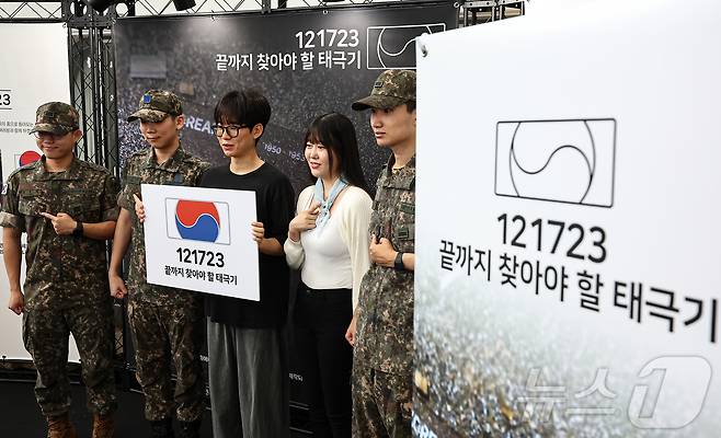 25일 서울 중구 서울역 대합실에 마련된 '태극기 부스'에서 군인들과 시민들이 태극기 배지를 패용 후 기념촬영 하고 있다. 2025.6.25/뉴스1 ⓒ News1 김도우 기자