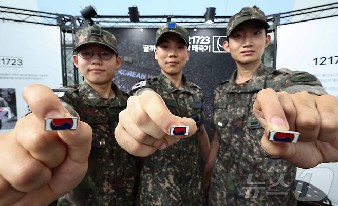 25일 서울 중구 서울역 대합실에 마련된 '태극기 부스'에서 군인들이 태극기 배지를 들어보이고 있다.  2025.6.25/뉴스1 ⓒ News1 김도우 기자
