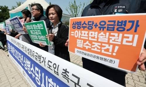 지난 2024년 5월 서울 여의도 국회의사당 정문 앞에서 열린 상병수당 본사업 시행연기 규탄 및 법정유급병가 도입 촉구 기자회견에서 아프면쉴권리공동행동 관계자들이 손팻말을 들고 있다. [사진 = 연합뉴스]