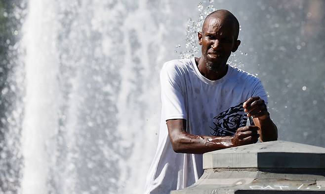 미국 뉴욕의 최고기온이 37.2도까지 오른 24일(현지시간) 뉴욕 워싱턴파크에서 한 시민이 분수대에서 물을 맞으며 더위를 식히고 있다. 뉴욕=UPI연합뉴스