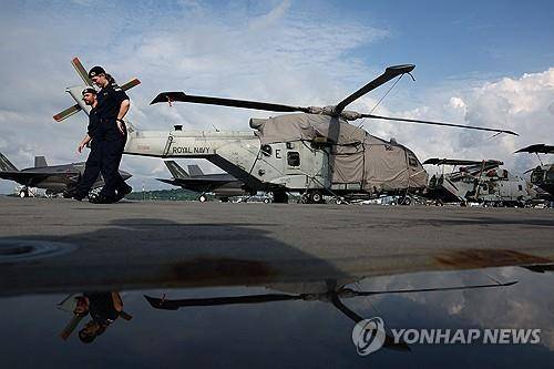 영국 항공모함 함상의 헬리콥터와 군인들 (싱가포르 로이터=연합뉴스) 2025년 6월 24일 싱가포르의 마리나베이 크루즈 센터에 입항해 있는 영국 해군 항공모함 '프린스오브웨일스' 함상에 있는 멀린 헬리콥터 옆을 군인들이 지나가고 있다. (REUTERS/Edgar Su) 2025.6.25.