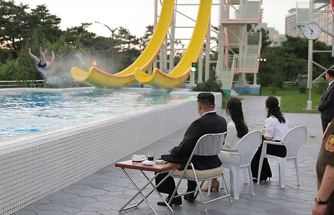 From left, North Korean leader Kim Jong-un, daughter Ju-ae, and wife Ri Sol-ju watch a man riding a water slide during a completion ceremony for the Wonsan-Kalma Coastal Tourist Zone on June 24. /News1