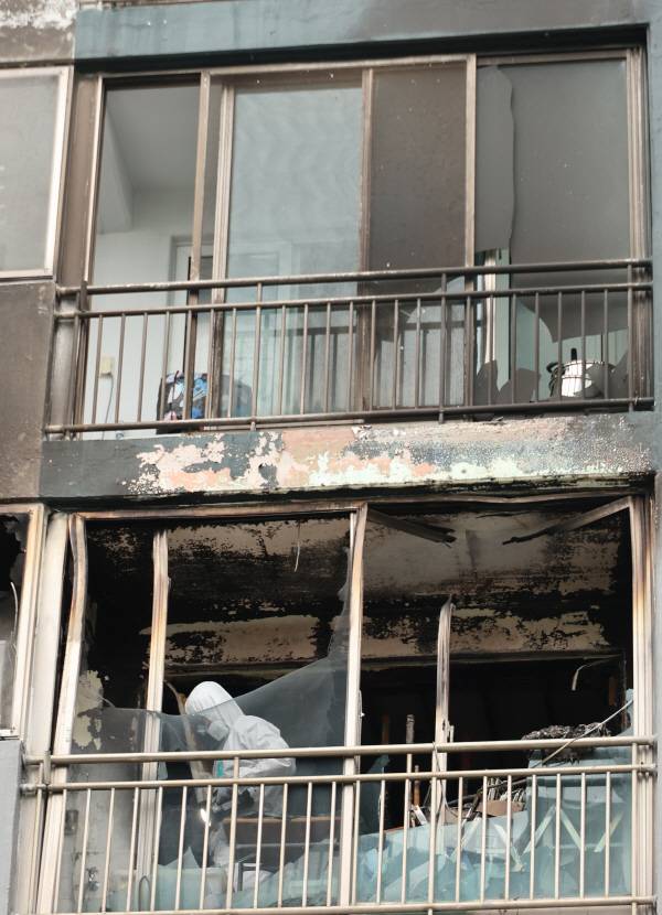 지난 24일 화재로 자매가 숨진 부산 한 아파트 현장에서 소방과 경찰이 합동 감식을 벌이고 있다. 연합뉴스