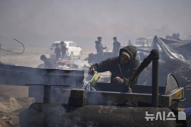 <font style="vertical-align: inherit;"><font style="vertical-align: inherit;">[가자시티=AP/뉴시스] 지난 22일(현지 시간) 가자지구 가자시티 남쪽 시로드에서 팔레스타인인이 플라스틱에서 추출한 연료를 식히기 위해 물을 사용하고 있다. 팔레스타인 청년들은 플라스틱 폐기물을 금속 드럼에 넣고 가열해 만든 연료를 병에 담아 판매하며, 이는 현지에서 발전기나 이동용 연료로 사용된다. 유독한 연기와 불길에 노출되는 고된 작업이지만, 이들에게는 가족의 생계를 이어가는 거의 유일한 수단이다. 2025.06.25.</font></font>