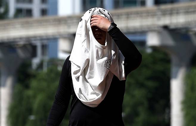 전국이 30도 안팎의 무더운 날씨를 보인 23일 대구 북구 동천교에서 한 시민이 겉옷으로 햇빛을 가리고 있다. 뉴시스