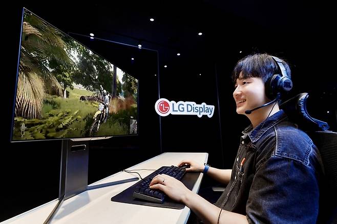 LG디스플레이 모델이 4세대 기술이 적용된 27인치 유기발광다이오드(OLED) 모니터 패널로 게임을 즐기고 있다. (사진=LG디스플레이)