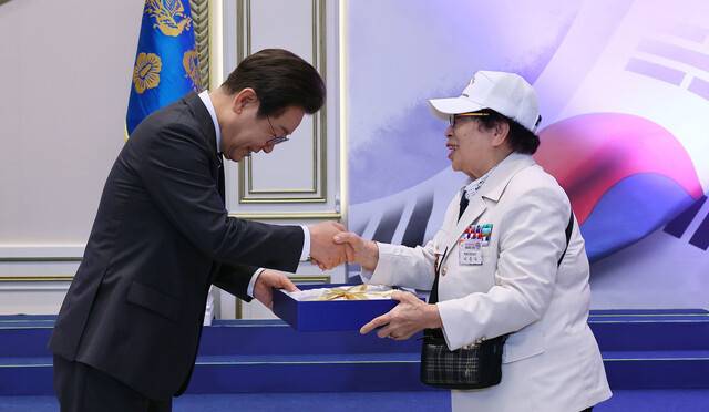 이재명 대통령이 27일 청와대 영빈관에서 열린 ‘호국보훈의 달, 대통령의 초대’에서 이춘자 참전유공자에게 선물을 전달하고 있다. 대통령실사진기자단