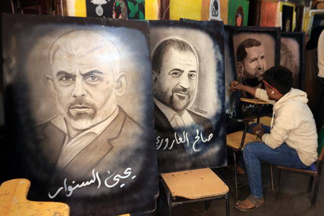 예멘의 한 예술가가 23일 수도 사나에서 열린 '이란과 연대를 위한 공동 예술 워크숍'에서 지난해 사망한 하마스 수장 야히아 신와르(왼쪽부터)와 하마스 부총재 살레 알 아로리를 그린 그림 옆에서 작업을 하고 있다. 사나=EPA 연합뉴스