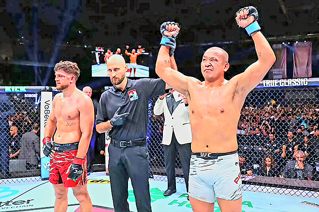 박준용이 반칙을 당한 눈을 뜨지 못한 채 2025년 6월 아제르바이잔 바쿠 크리스털 홀 UFC on ABC 8 제5경기 승리 선언을 받고 있다. 왼쪽은 이스마일 나우르디예프. 사진=TKO