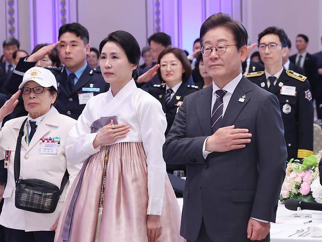 이재명 대통령과 김혜경 여사가 27일 청와대 영빈관에서 열린 ‘호국 보훈의 달, 대통령의 초대’ 행사에서 국기에 경례하고 있다.  이번 행사에는 국가유공자 및 유족, 보훈단체장, 특별초청자 등이 참석했다. [연합]