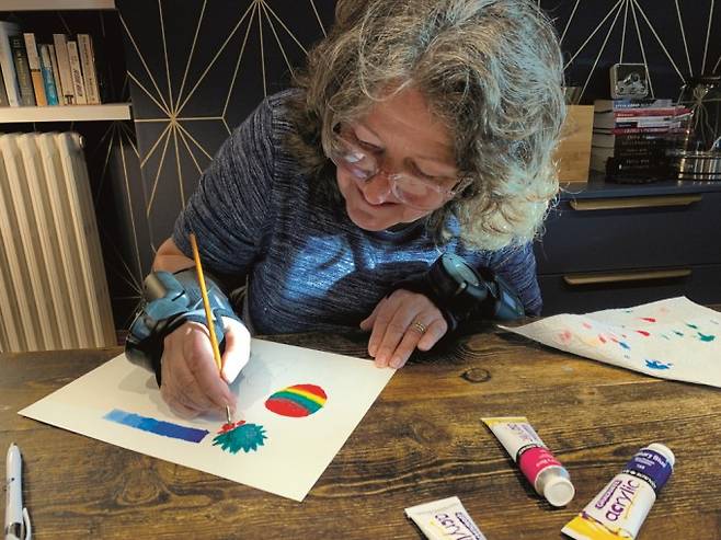 30대 무렵 수전증 증상이 심해진 영국의 70대 수전증 환자 사라 호든씨는 2024년 자이로기어의 수전증 완화 장갑인 자이로글로브를 착용한 후로 게임이나 그림 그리기 등을 하며 일상을 되찾았다. Gyrogear 제공