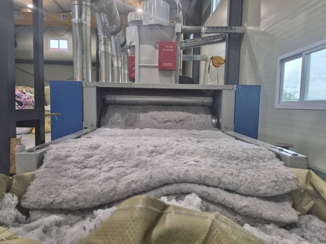 지난 20일 충북 진천의 한 의류 재활용 공장에서 파쇄와 압축 공정을 거친 천 조각들이 기계 밖으로 쏟아져 나오고 있다.