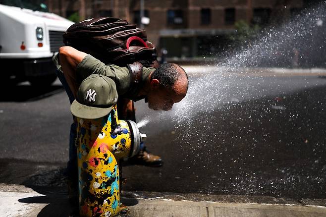 25일(현지시간) 미국 뉴욕 맨해튼 해밀턴 하이츠 지역의 소화전에서 한 남성이 물을 맞으며 더위를 식히고 있다. /AFPBBNews=뉴스1