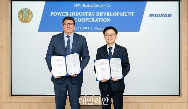 카자흐스탄 알마싸담 삿칼리에브 에너지부 장관(왼쪽)과 두산에너빌리티 김정관 마케팅부문장이 23일 두산에너빌리티 창원 본사에서 ‘카자흐스탄 발전산업 개발 협력’을 위한 양해각서(MOU)을 체결한 뒤 기념촬영을 하고 있다. ⓒ두산에너빌리티
