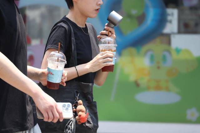 28일 대구에 폭염경보가 내려진 가운데 중구 동성로에서 시민들이 아이스 아메리카노와 휴대용 선풍기로 더위를 식히면서 이동하고 있다. 연합뉴스