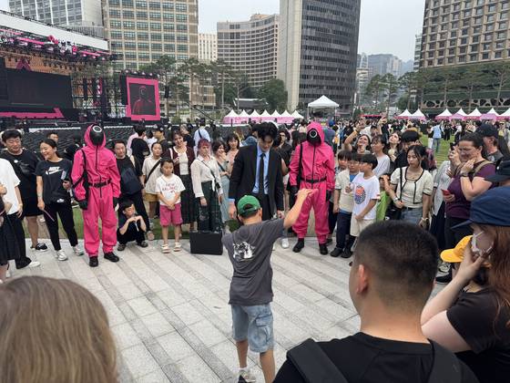 A child is playing ddakji chigi (throwing folded paper) against the Recruiter at Seoul Plaza in central Seoul on June 28. [KIM JI-YE]