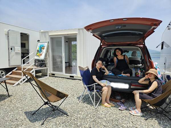지난해 아트경남 아트쇼 참가를 계기로 알게 돼 올해는 THEE라는 팀으로 참가한 탁하린·정진경·류엘리(왼 쪽부터) 작가가 카라반 옆으로 주차한 자동차 트렁크에 깐 매트와 캠핑용 의자에 앉아 나들이를 온 것처럼 자연 속 아트쇼를 만끽하고 있다. 백지영기자