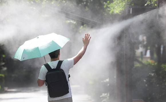 대구 중구 국채보상운동기념공원에 쿨링포그(안개형 냉각수)가 가동 중인 가운데 한 시민이 양산을 들고 이동하고 있다. [사진=연합뉴스]