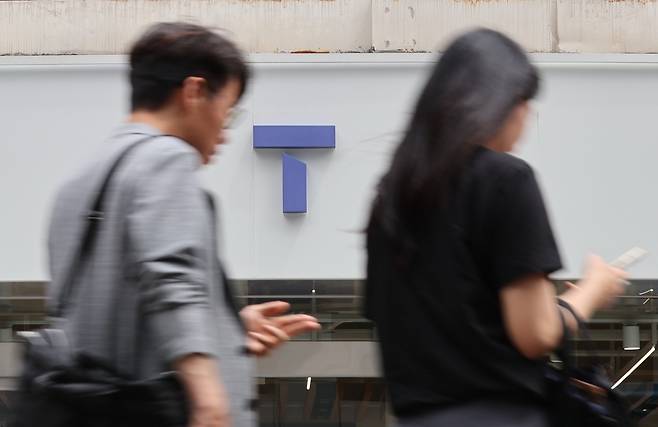 People walk past an SK Telecom branch in Seoul on June 24. (Yonhap)