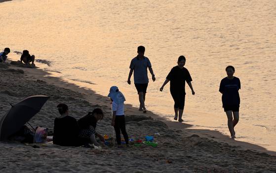 People cool off by dipping their feet in the sea or enjoying the ocean breeze at a beach in Gangneung, Gangwon, on June 29. [YONHAP]