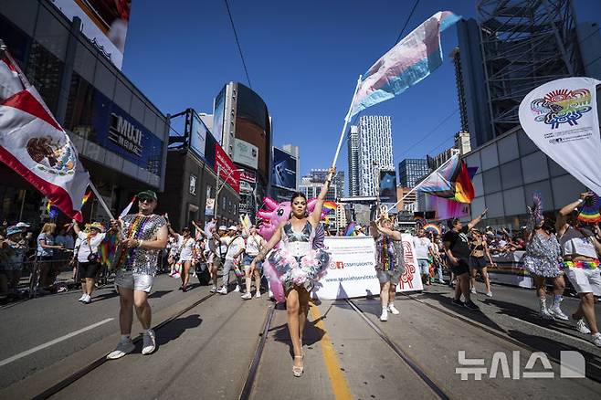 [토론토=AP/뉴시스] 29일(현지 시간) 캐나다 온타리오주 토론토에서 열린 프라이드 퍼레이드에서 참가자들이 깃발을 흔들며 행진하고 있다. 매년 6월은 '세계 성소수자 프라이드의 달'로 세계 곳곳에서 기념행사가 열린다. 2025.06.30.