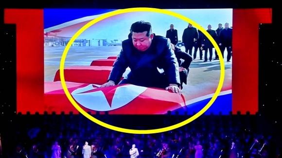 북한 조선중앙TV가 지난 29일 동평양대극장에서 방북 중인 올가 류비모바 러시아 문화부 장관이 참석한 가운데 열린 예술인 공연 중 무대 배경화면에 김정은(노란색 원) 국무위원장이 러시아 파병 북한군 전사자 관을 어루만지며 애도하는 장면을 30일 공개했다. 2025.6.30 조선중앙TV 화면 연합뉴스