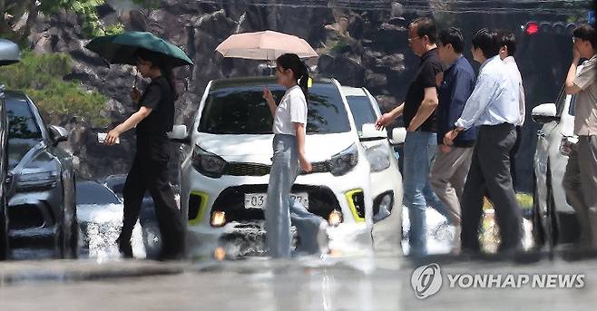'폭염' (대구=연합뉴스) 윤관식 기자 = 대구에 올해 첫 폭염주의보가 발령된 27일 대구 북구 오봉오거리 인근 도로에 지열로 인한 아지랑이가 피어오르는 가운데 시민들이 도로를 건너고 있다. 2025.6.27 psik@yna.co.kr
