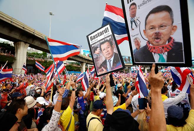 /EPA 연합뉴스28일 태국 방콕에서 열린 패통탄 친나왓 태국 총리 사퇴 촉구 시위에서 참가자들이 태국 국기를 휘날리는 와중 훈센 캄보디아 상원의장 사진에 욕설을 쓴 피켓을 들어보이고 있다.