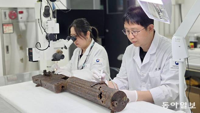 국립문화유산연구원 이재성 학예연구사(오른쪽)와 윤혜성 학예연구원이 비무장지대(DMZ)에서 출토된 기관총의 이물질을 제거하고 있다. 두 사람은 “원형을 최대한 구체적으로 파악하고자 총기류 백과사전을 펴가며 공부했다. 고대 유물을 보존 처리할 때보다 뭉클함이 크다”고 했다. 대전=이지윤 기자 leemail@donga.com