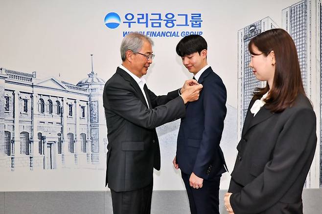 1일 임종룡 우리금융그룹 회장(왼쪽)이 그룹의 새 가족이 된 동양생명·ABL생명 직원에게 디지털 선도의 의미가 담긴 새로운 그룹 보조휘장을 달아주고 있다. 우리금융 제공