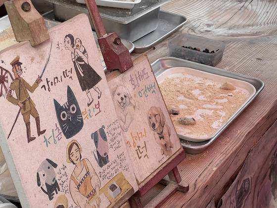 Free samples of gangaji tteok, or North Korean-style rice cakes with red bean paste inside, are offered at Daeryong Market on June 27. [LEE TAE-HEE]