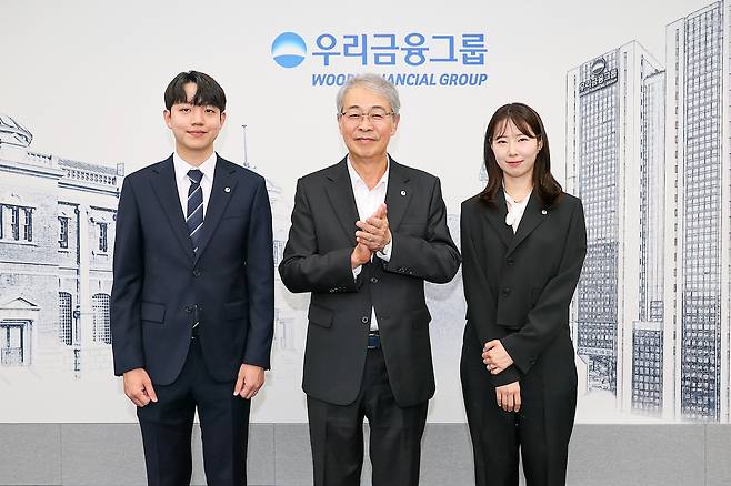 임종룡(가운데) 우리금융그룹 회장이 그룹의 새 가족이 된 동양생명·ABL생명 직원에게 디지털 선도의 의미가 담긴 새로운 그룹 보조휘장을 달아주고 기념촬영하고 있다  [우리금융그룹 제공]