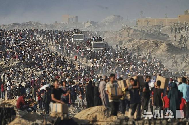 [가자시티(가자지구)=AP/뉴시스]팔레스타인인들이 지난 16일 가자시티로 향하던 세계식량계획(WFP) 구호 트럭에서 받은 식량과 인도주의적 원조 물품을 담은 자루와 상자 등을 들고 있다. 이스라엘군과 드론이 24일 새벽 가자지구 중심부에서 구호 트럭을 기다리던 팔레스타인인 수백명을 향해 총격을 가해 최소 25명이 사망했다고 팔레스타인 목격자들과 병원들이 밝혔다. 2025.06.14