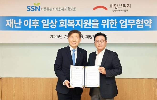 신훈 희망브리지 사무총장(오른쪽)과 김현훈 서울시사회복지협의회 회장이 재난취약계층 일상 회복지원을 위한 업무협약서에 서명한 뒤 기념촬영을 하고 있다. 희망브리지 제공