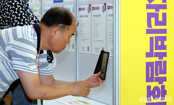 1일 서울 중구 동대문디자인플라자(DDP)에서 열린 서울시 중장년 일자리박람회 2025에서 한 구직자가 채용공고 게시대를 스마트폰으로 촬영하고 있다.