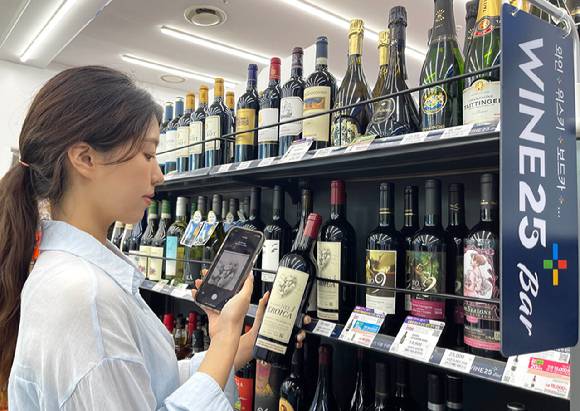 모델이 우리동네GS 앱 내 와인25플러스의 AI 이미지 검색 기능으로 와인을 확인하고 있다. [사진=GS리테일]