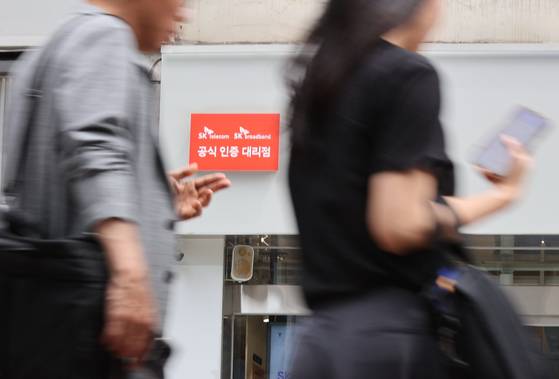 People walk by an SK Telecom store in downtown Seoul on June 24. [YONHAP]
