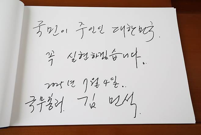 김민석 국무총리가 4일 서울 동작구 국립서울현충원에서 참배를 마친 후 방명록에 "국민이 주인인 대한민국, 꼭 실현하겠습니다"라고 쓰고 있다.